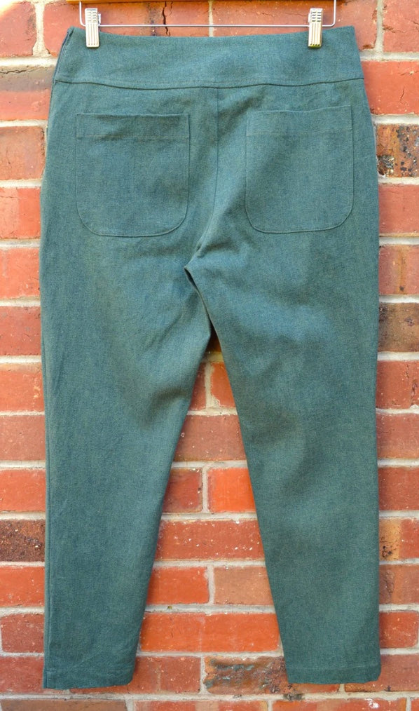 Green pants hanging on a brick wall