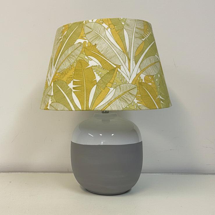 Table lamp with a green leaf-patterned shade on a white surface.