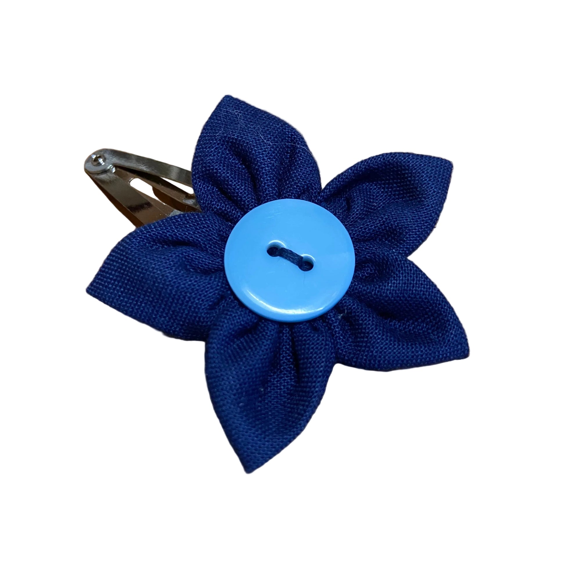 Blue fabric flower hair clip with a button center on a wooden surface