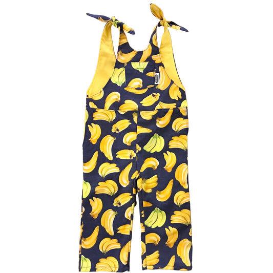 Navy blue romper with yellow banana pattern hanging on a wooden surface