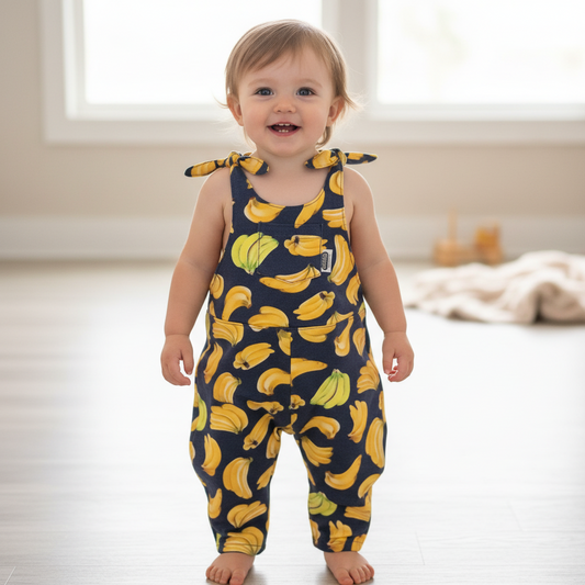 Navy blue romper with yellow banana pattern hanging on a wooden surface