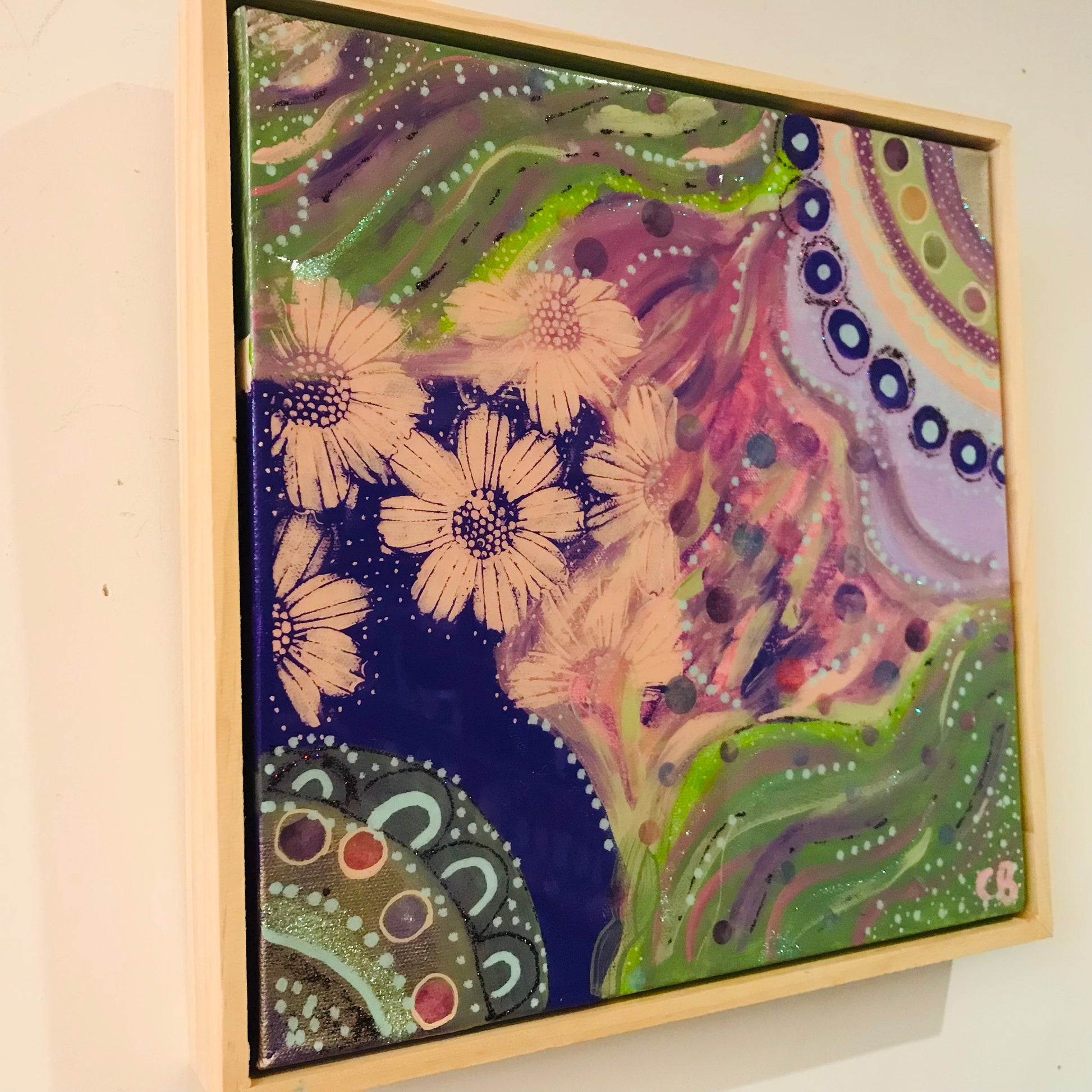 Framed abstract artwork with floral elements on a beige wall