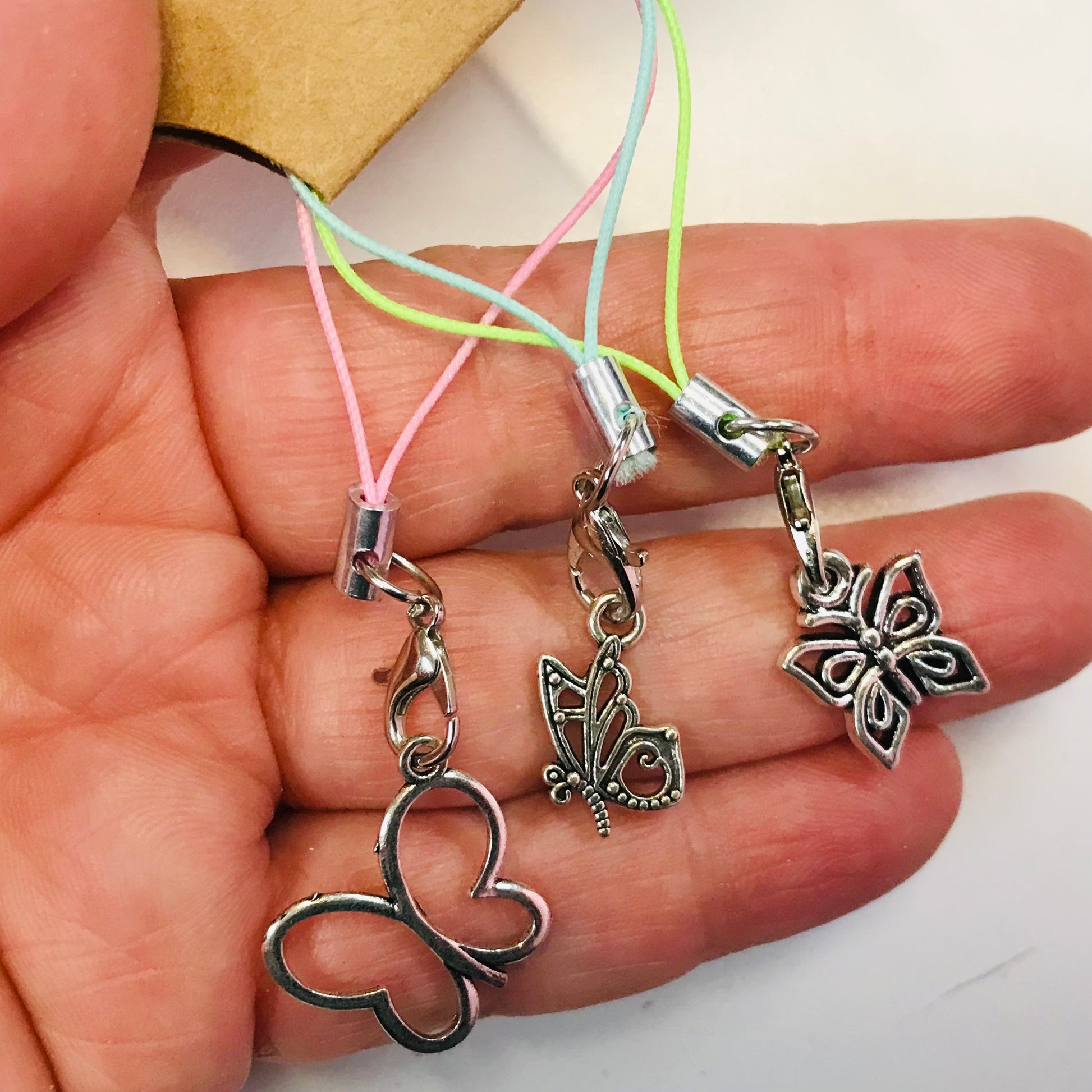 Butterfly-shaped charms on colorful strings held in a hand.