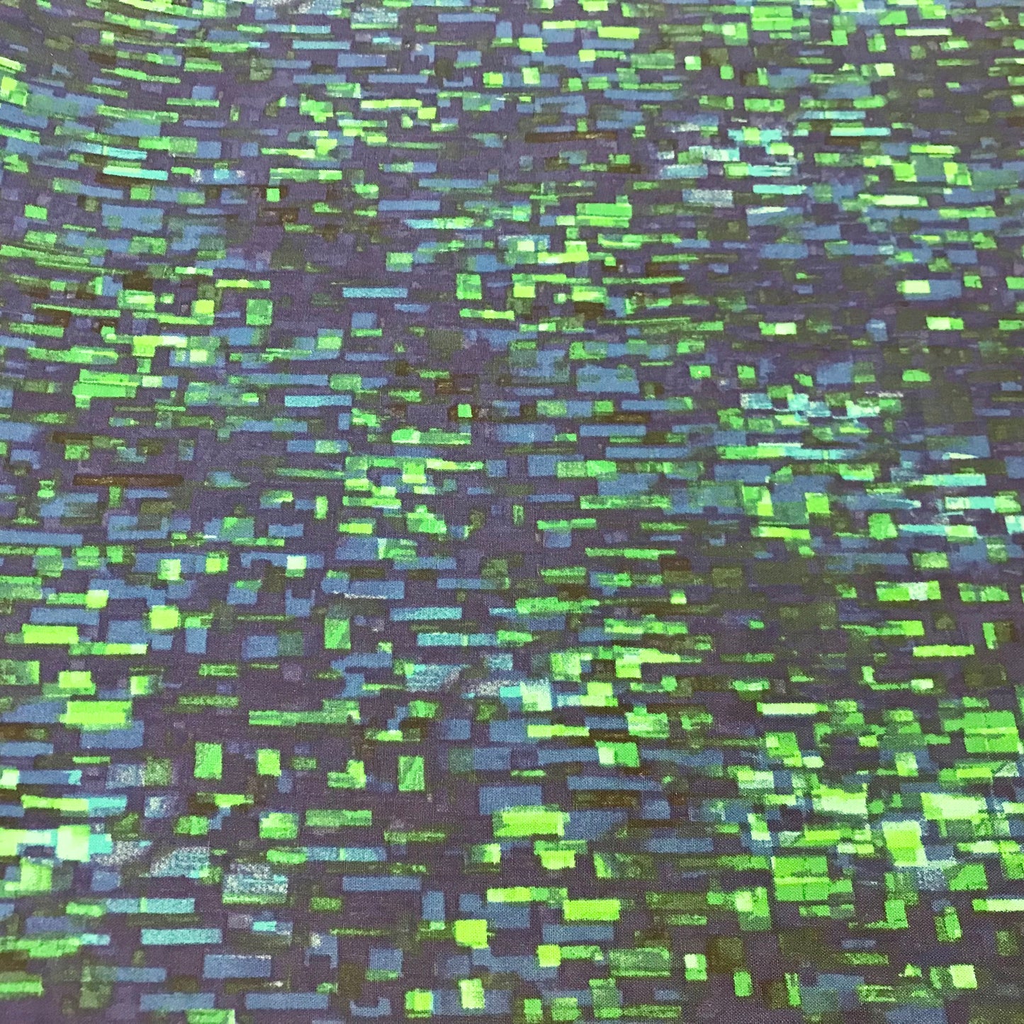 Patterned fabric with green and blue rectangular shapes on a dark background