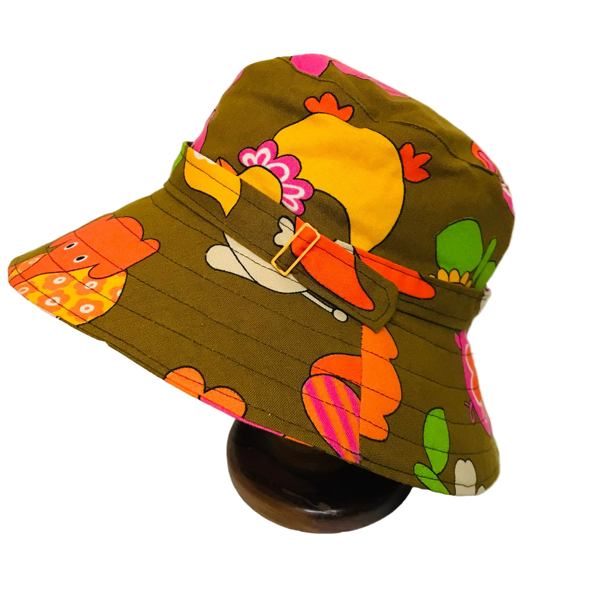 A vintage-style bucket hat with a retro animal and floral print, displayed on a dark wooden stand against a plain white background.