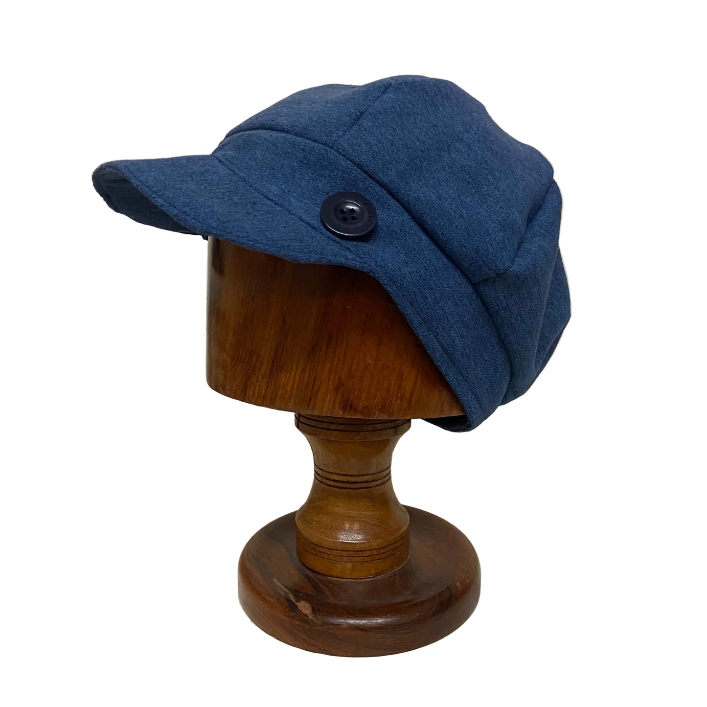 Blue cap on a wooden mannequin head against a plain background