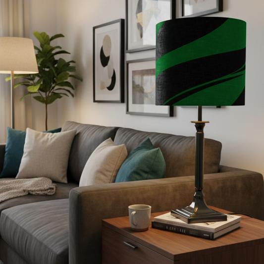 A table lamp with a black and bright green patterned drum shade, a black cylindrical stem, and a square black base, shown against a plain off-white wall.