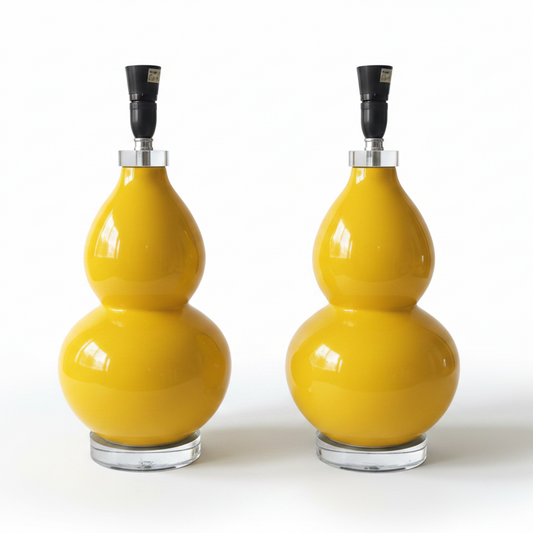 Two matching glossy yellow gourd-shaped table lamps with black lamp fittings and clear round bases, photographed on a clean white studio background.