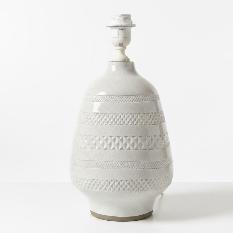 A white ceramic table lamp with a textured, ribbed pattern and a white cord, sitting on a white background