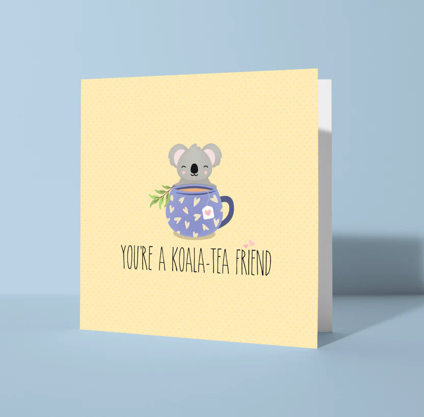 Greeting card with a koala holding a mug and text 'You're a Koala-Tea Friend' on a light blue background