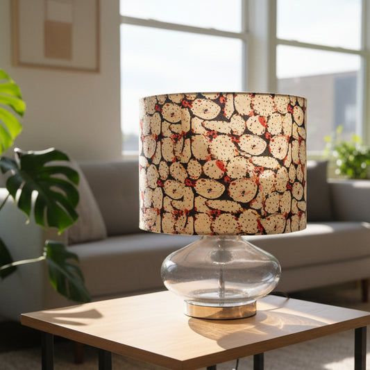 Patterned LAMP SHADE on a GLAS LAMP BASE ON A TABLE IN A LIVING ROOM