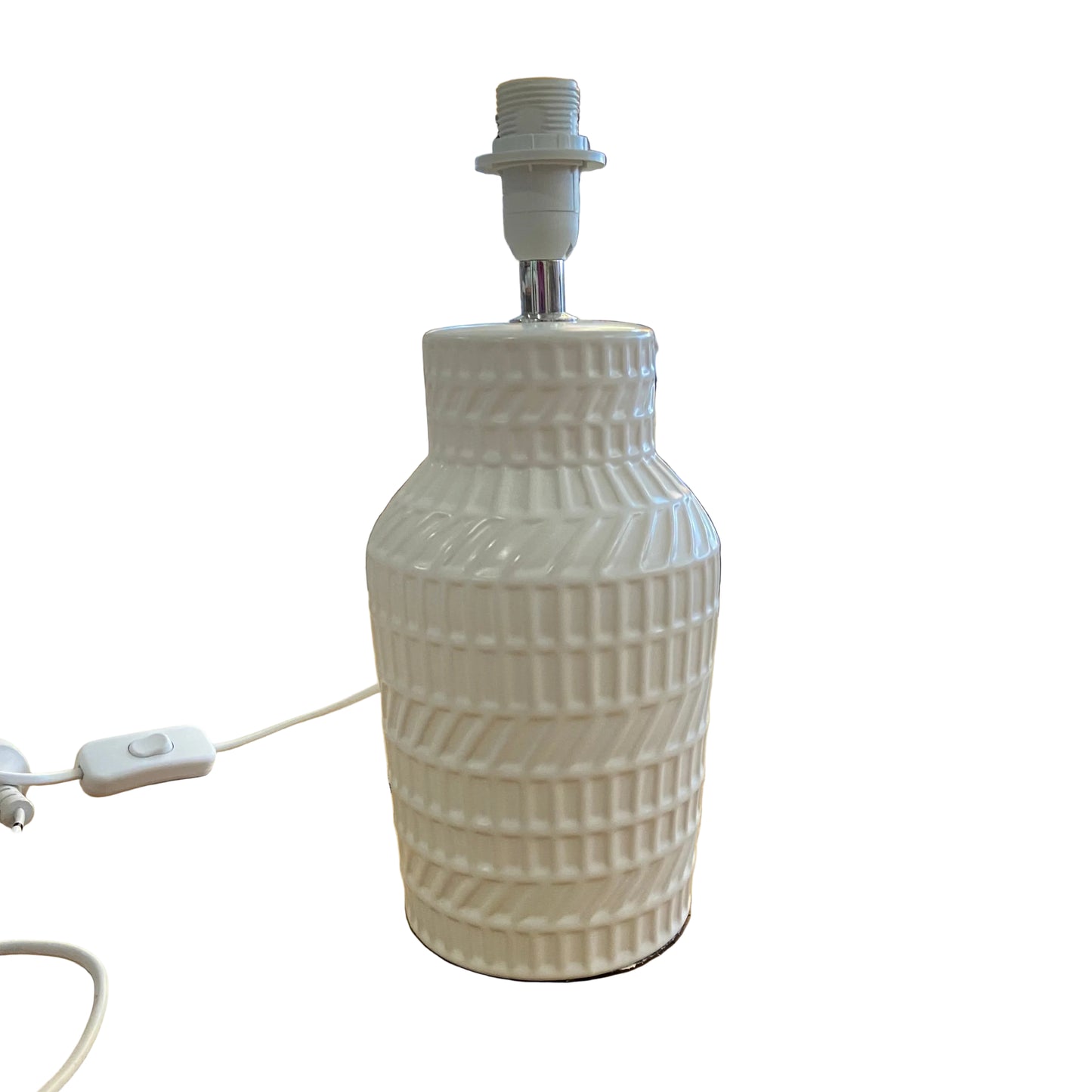 A white ceramic table lamp with a ribbed textured base and a white socket on top, sitting on a wooden table inside a retail shop.