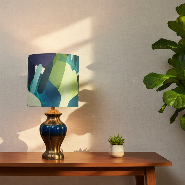 Decorative lamp with a colorful shade on a wooden table next to a plant.