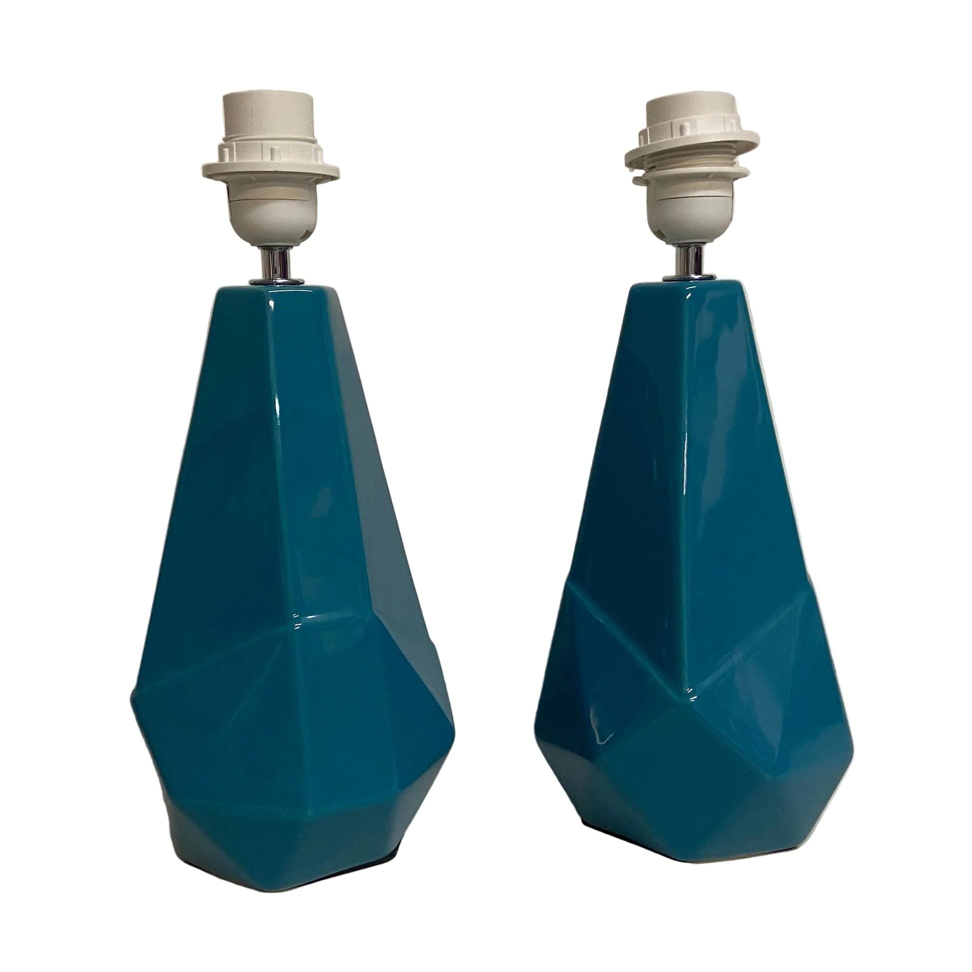 Two blue geometric lamps on a light-colored surface with a neutral background.