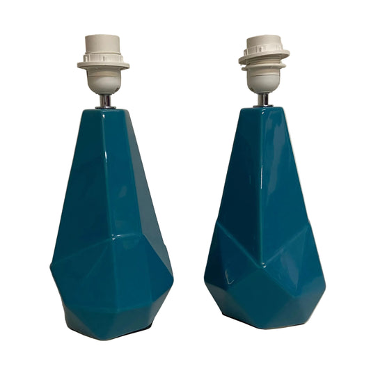 Two blue geometric lamps on a light-colored surface with a neutral background.