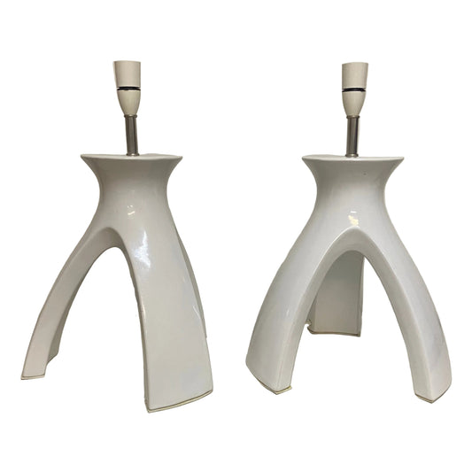 Two white ceramic table lamps on a white surface with a neutral background.