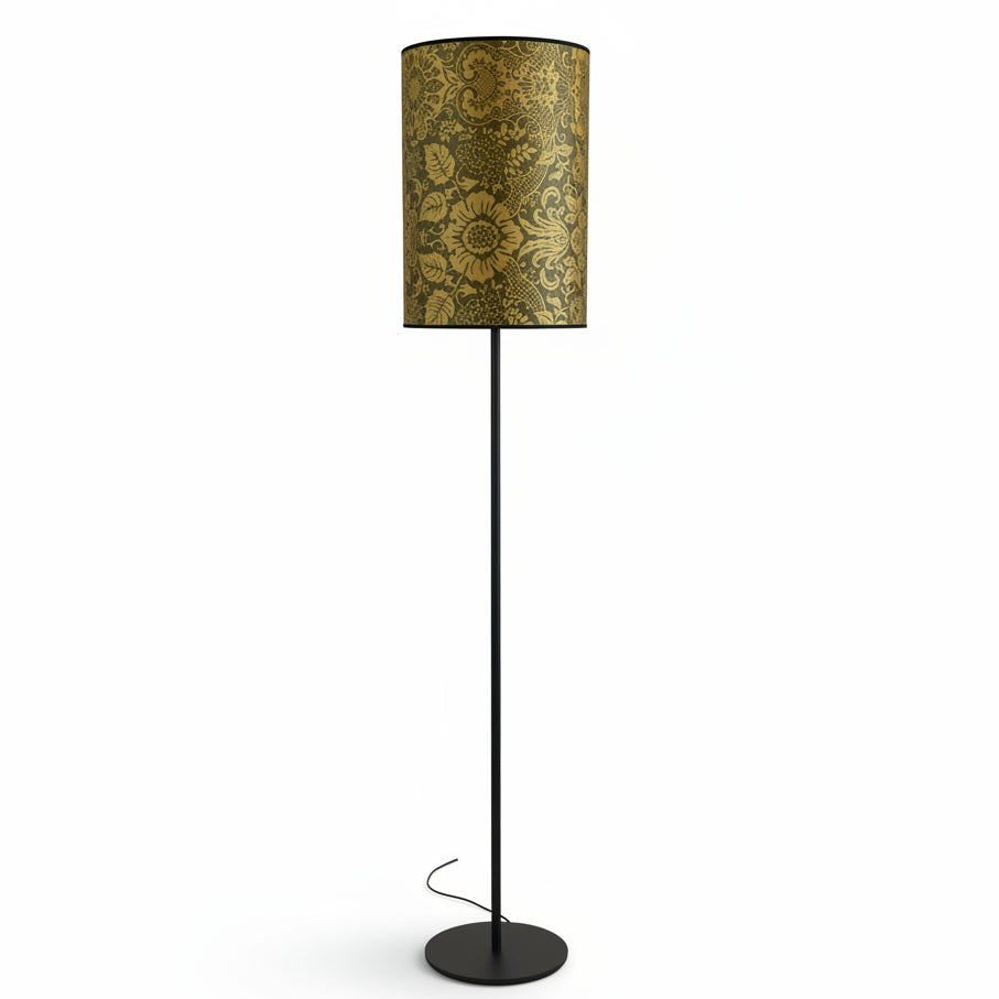 A tall floor lamp with a black metal stand and a large drum shade featuring a gold and brown floral damask pattern, shown on a white background.