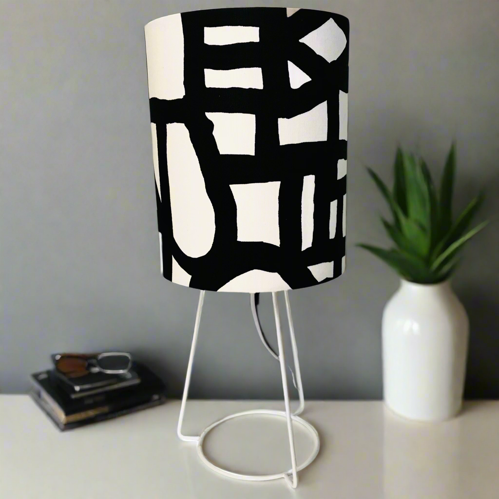 Table lamp with a black and white patterned shade on a white surface.
