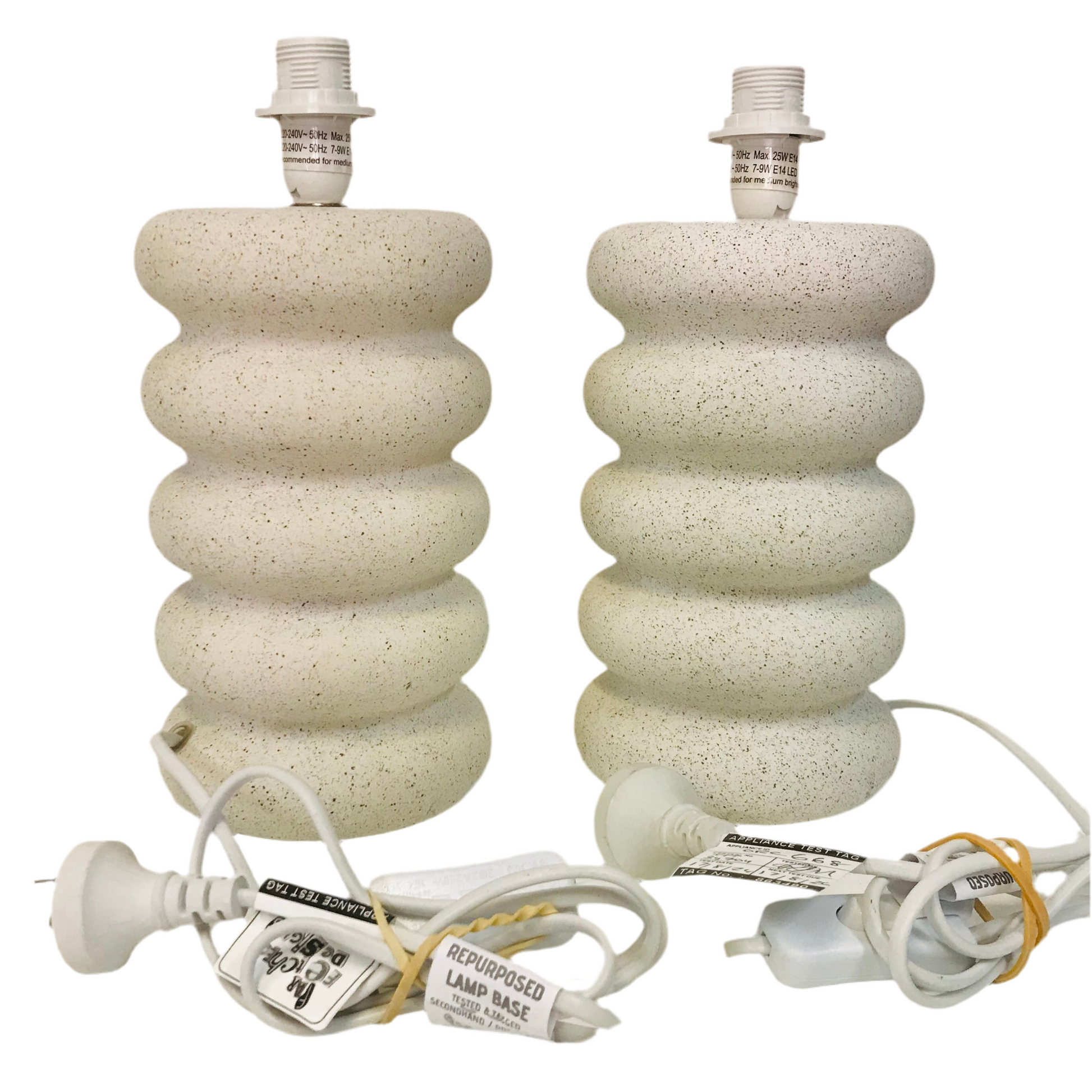 Two concrete table lamp bases with stacked boulders design, beige in color, accompanied by power cords but without shades.
