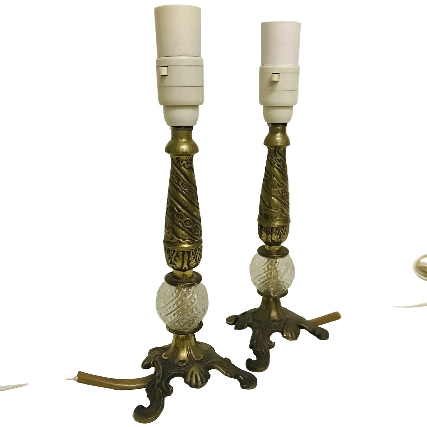 Two ornate brass lamps with white shades on a white surface.