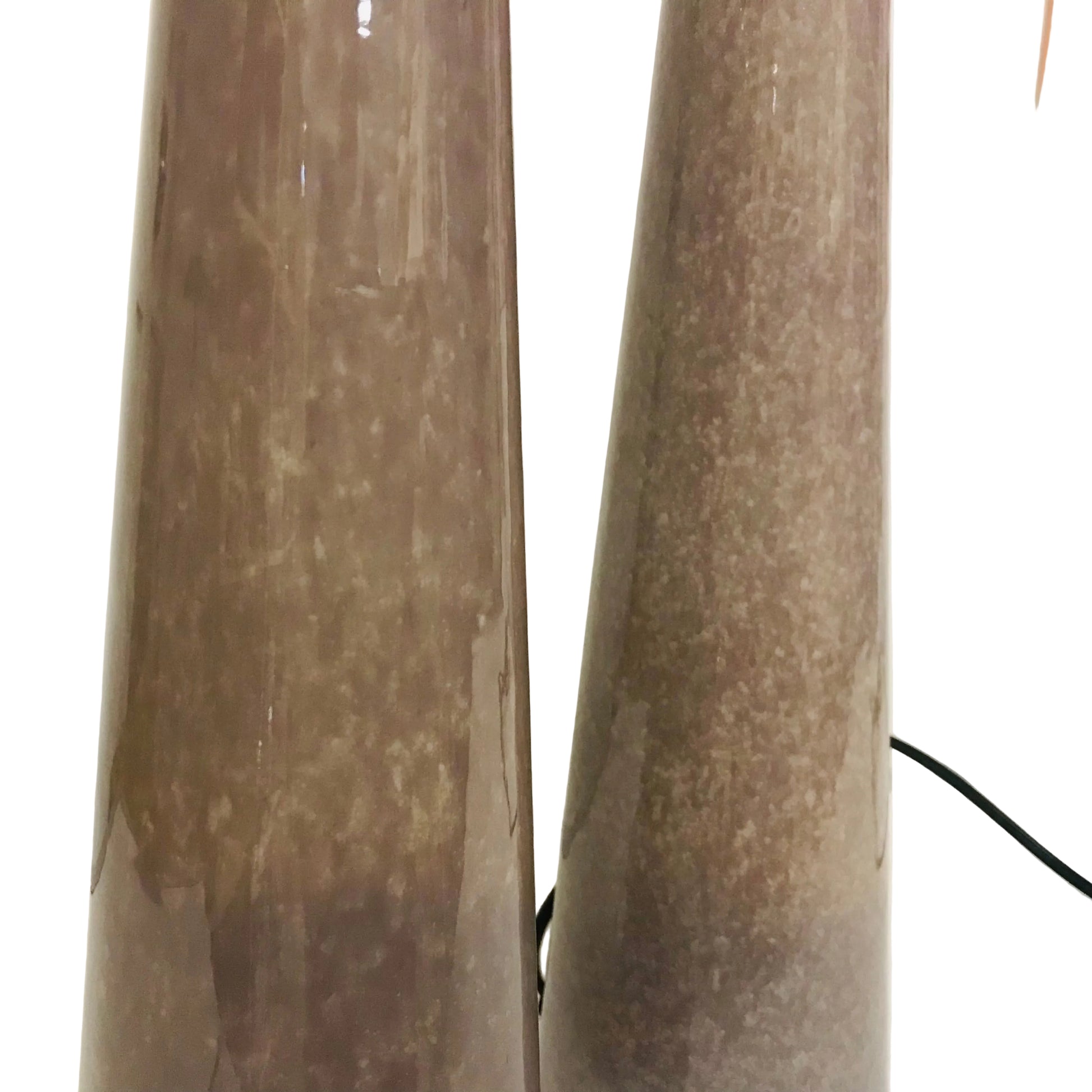 Two cylindrical brown lamps on a white surface with a light background