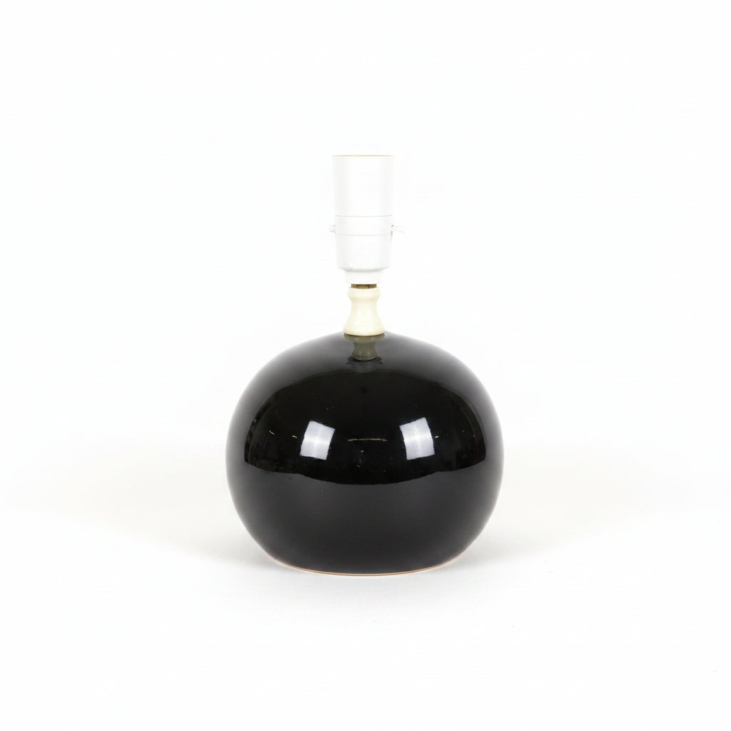 A vintage-style table lamp featuring a large, glossy black spherical glass base and a white ceramic neck and socket.