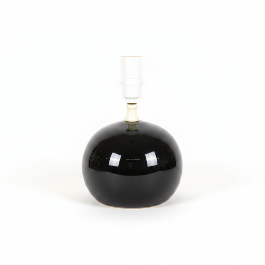 A vintage-style table lamp featuring a large, glossy black spherical glass base and a white ceramic neck and socket.