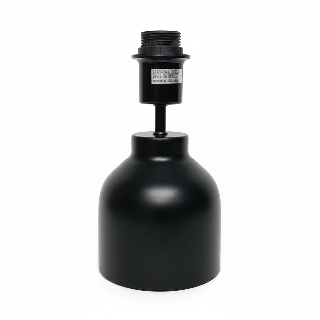 A black metal lamp base or light fixture component with a cylindrical shade-like body and threaded top, photographed against a plain off-white wall and surface.