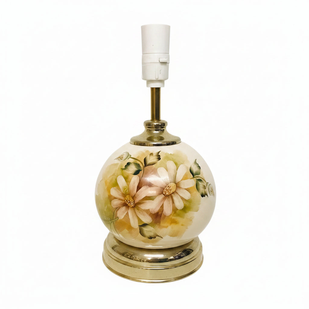 A vintage-style ceramic table lamp with a round white body decorated with hand-painted daisy flowers in soft pink, yellow, and green. The lamp features a gold-finished neck and base, with a white plastic light socket on top, set against a plain off-white background.