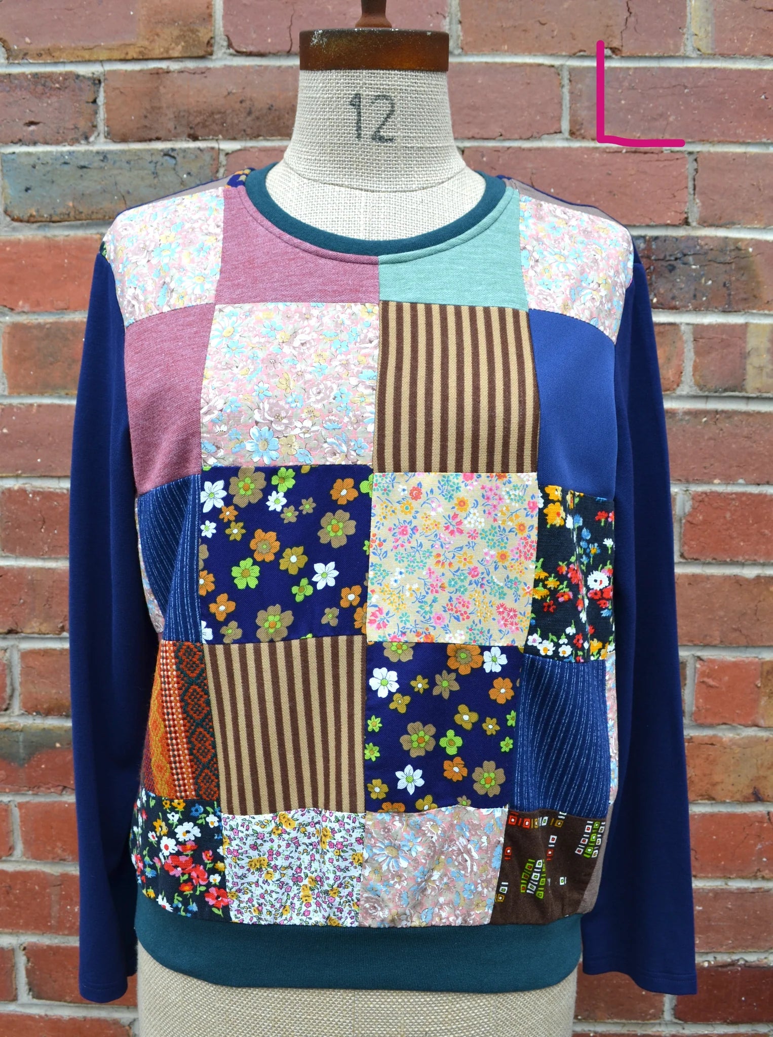 Patchwork sweater on a mannequin against a brick wall