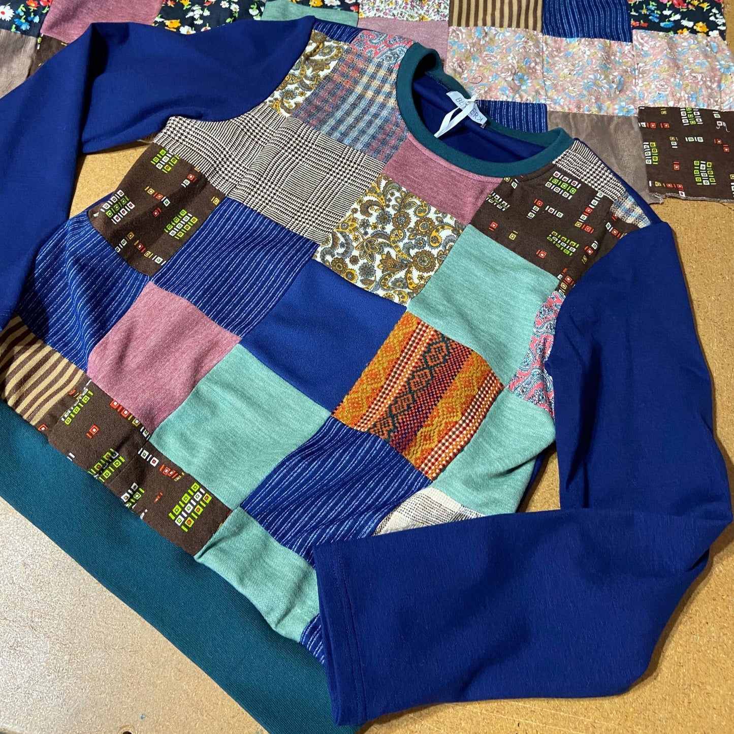 Blue sweater with a patchwork pattern on a wooden surface