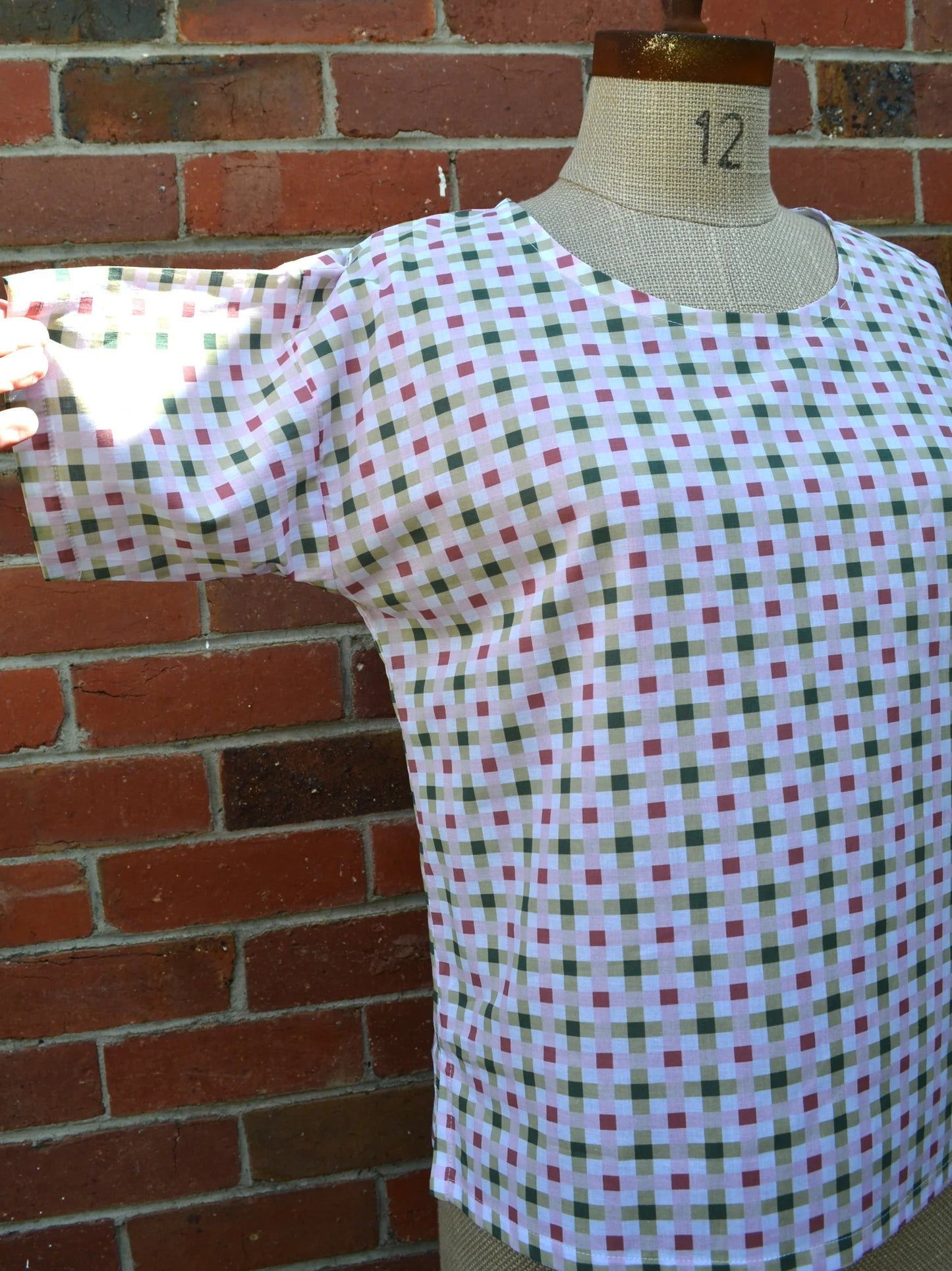 Plaid shirt on a mannequin against a brick wall