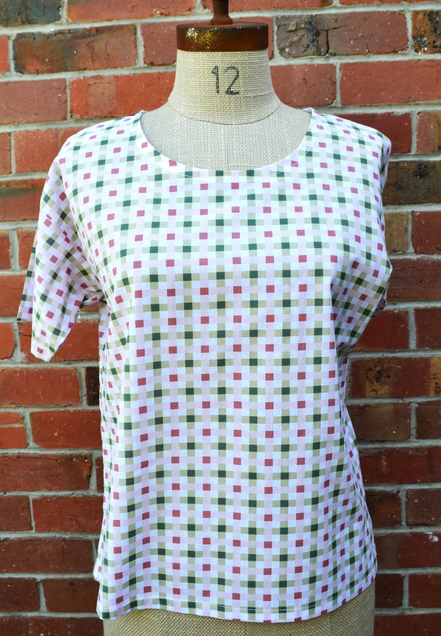 Plaid shirt on a mannequin against a brick wall