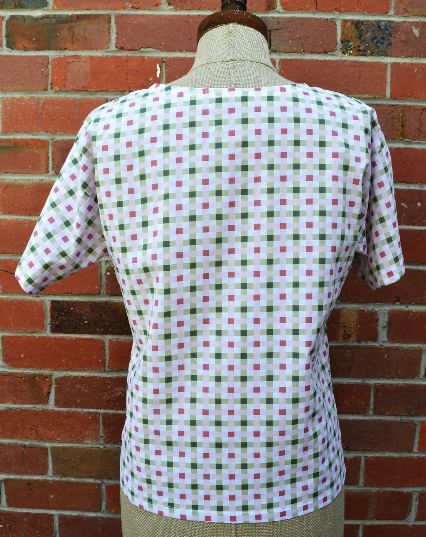 Mannequin wearing a checkered shirt against a brick wall