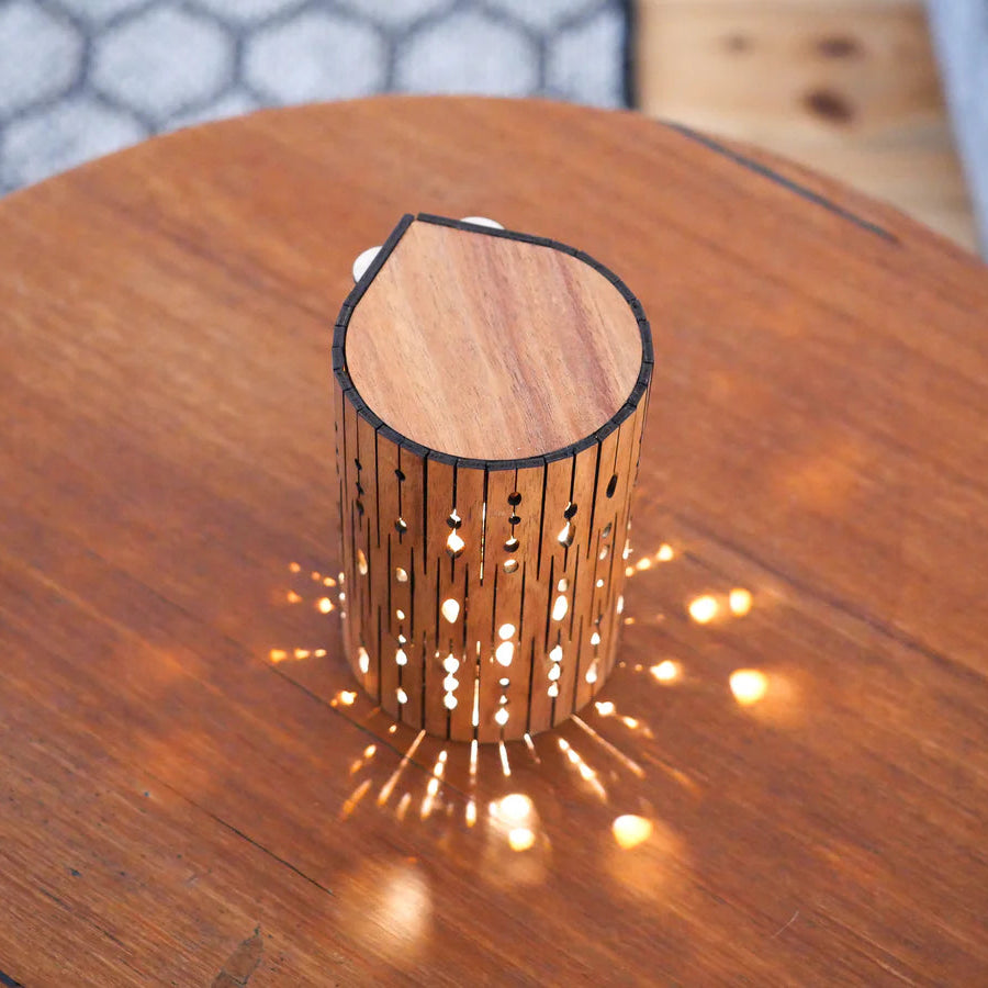 Wooden lamp with decorative cut-out design on a wooden table