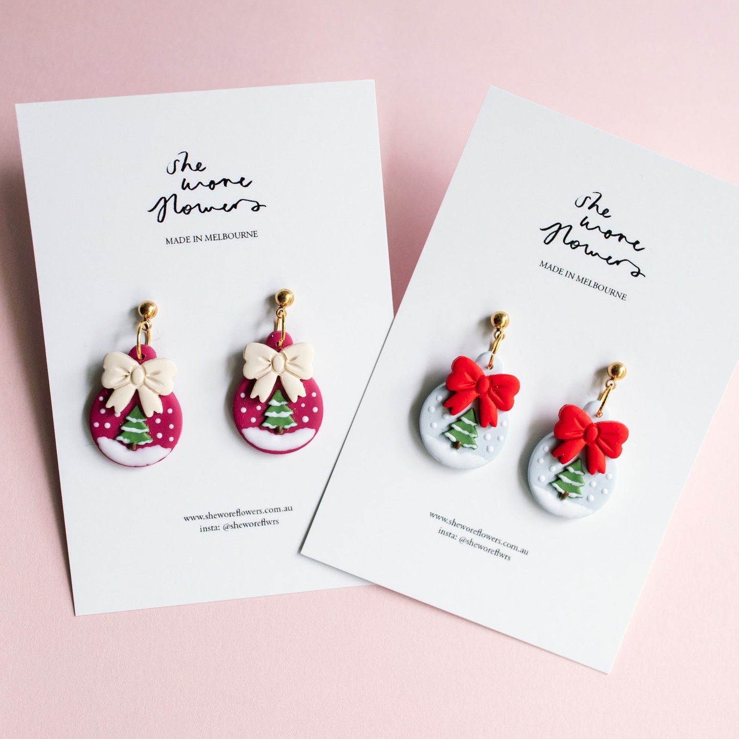 Set of Christmas-themed earrings on branded cards with a pink background