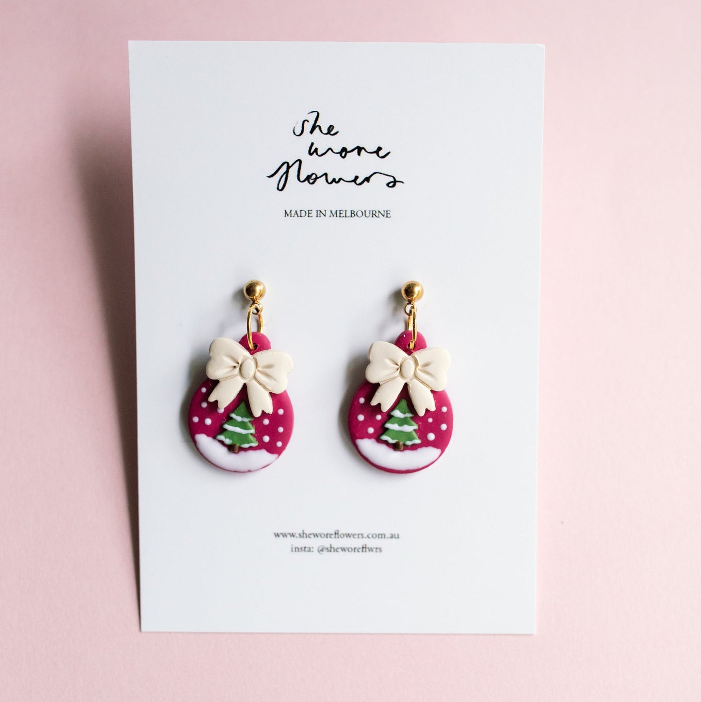Pair of earrings with pink and white polka dot design on a card with 'the wore flowers' branding.