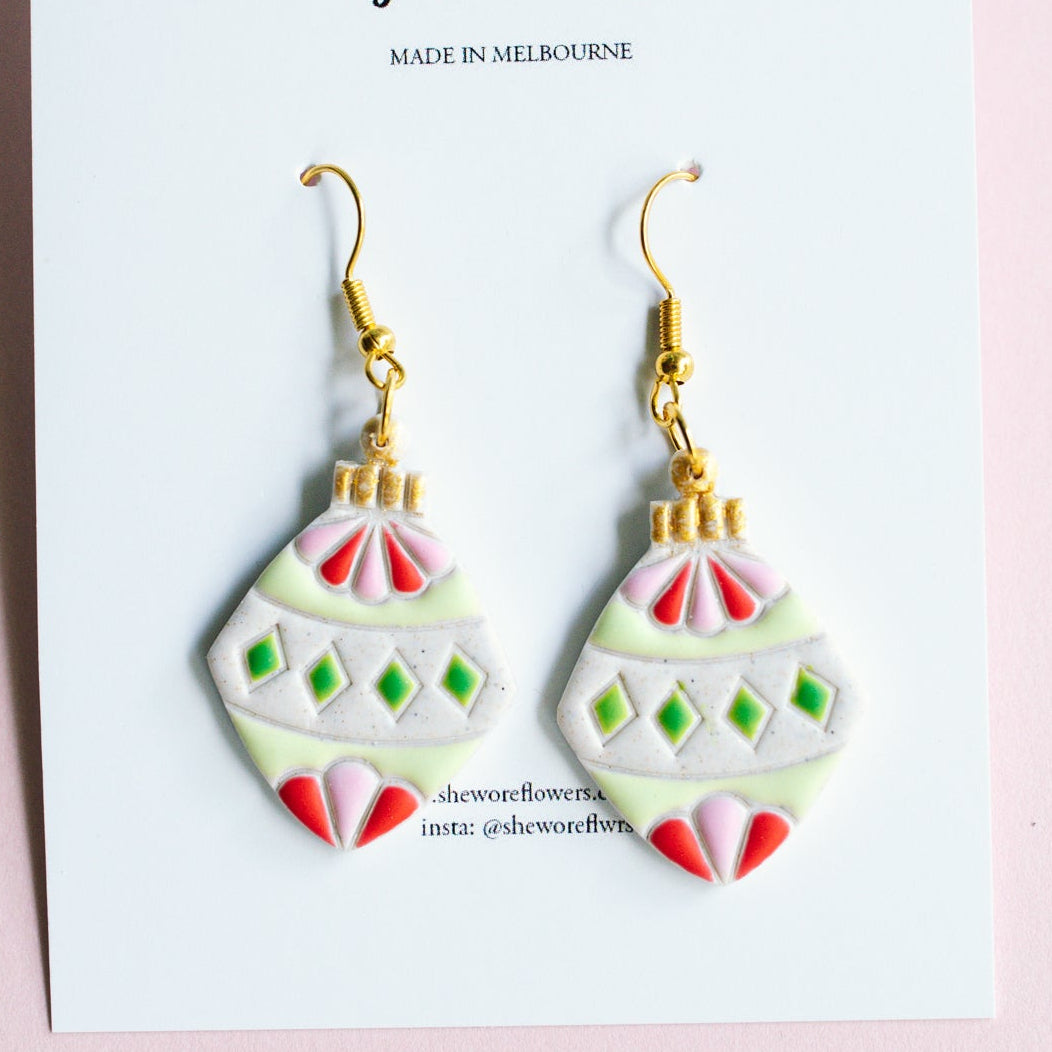 Pair of earrings on a card with 'the more flowers' branding on a pink background