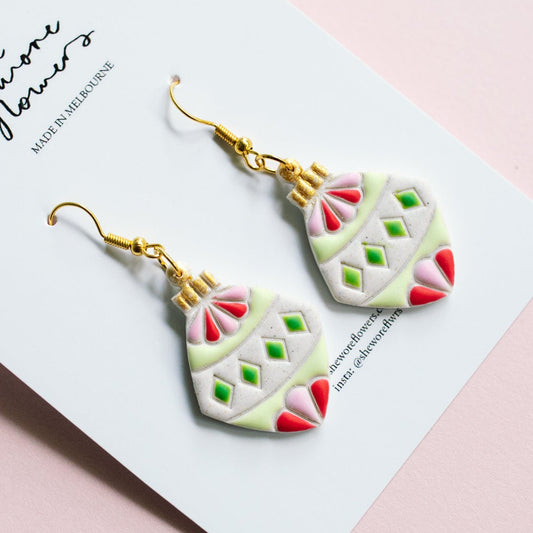 Decorative earrings on a card with a pink background