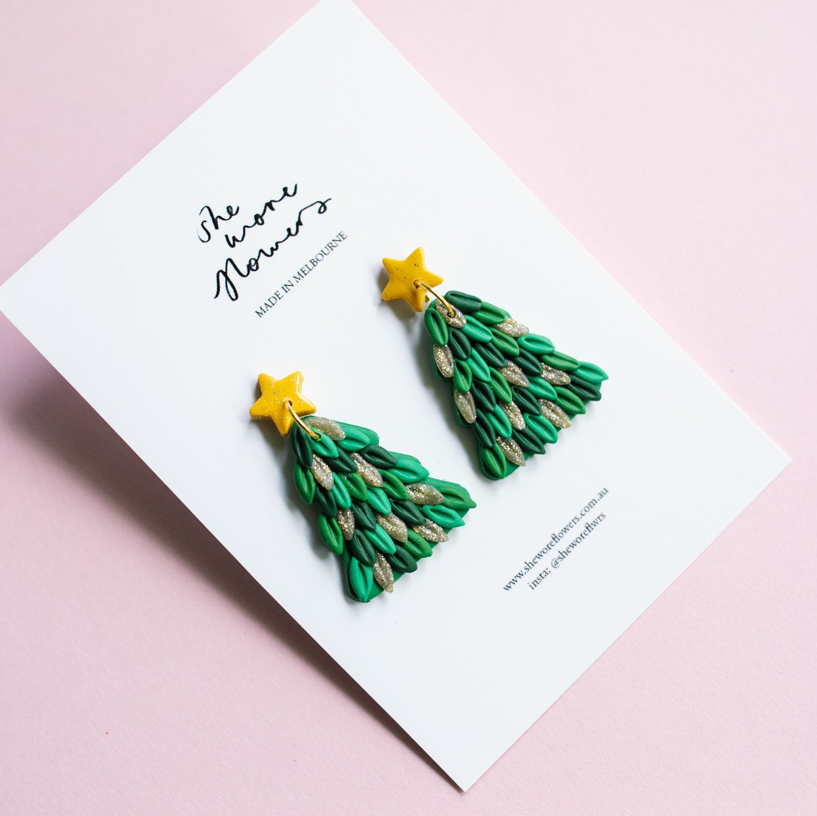 Green Christmas tree earrings on a white card with 'The Paper Flowers' branding on a pink background