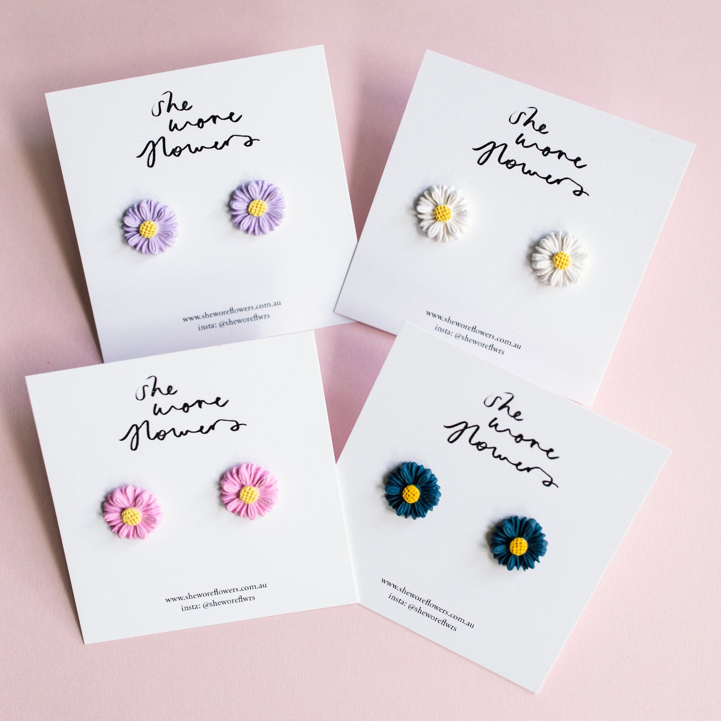 Set of floral earrings on branded cards against a pink background