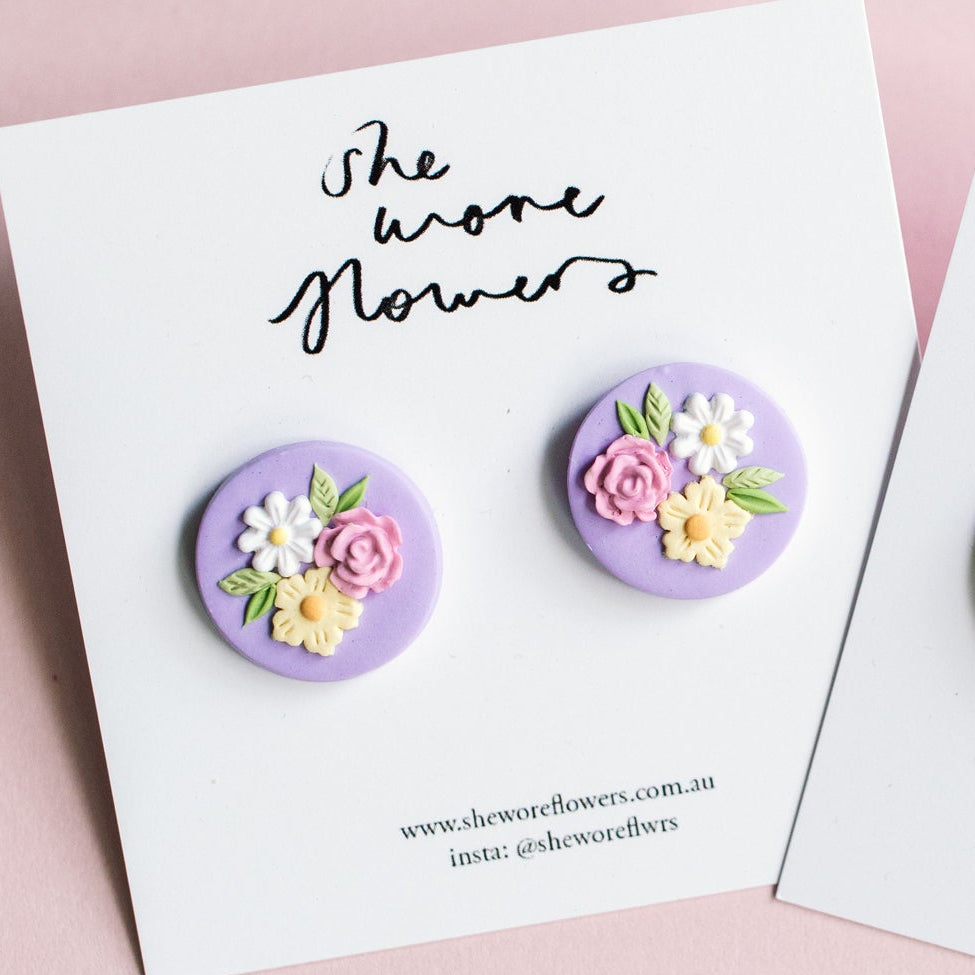 Floral earrings on cards with 'She wore flowers' text on a pink background