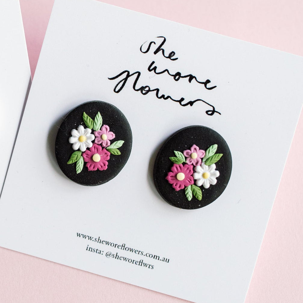 Floral earrings on cards with 'She wore flowers' text on a pink background