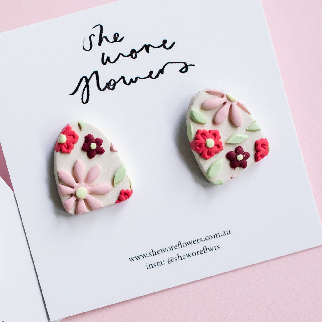 Floral earrings on cards with 'She wore flowers' text on a pink background