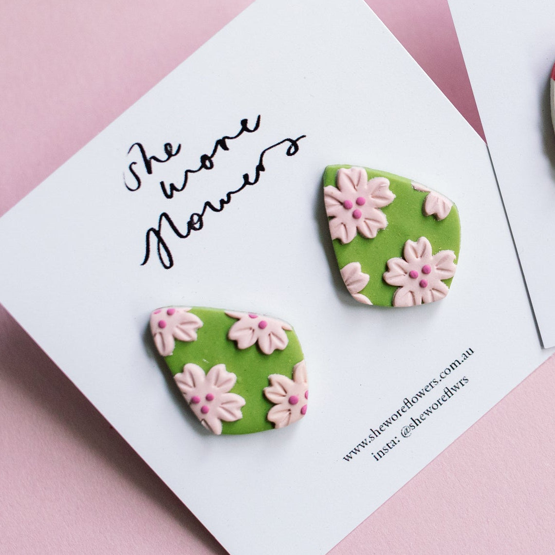 Floral earrings on cards with 'She wore flowers' text on a pink background