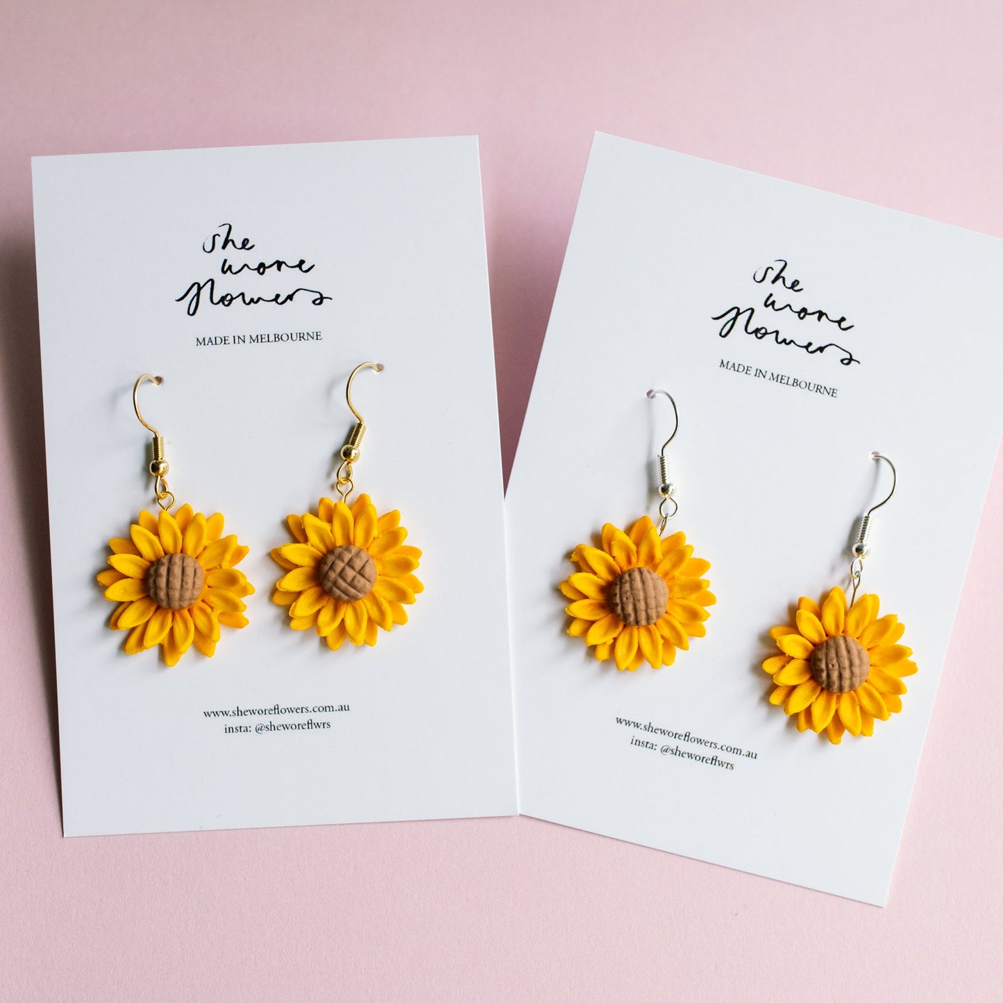 Sunflower earrings on branded cards against a pink background
