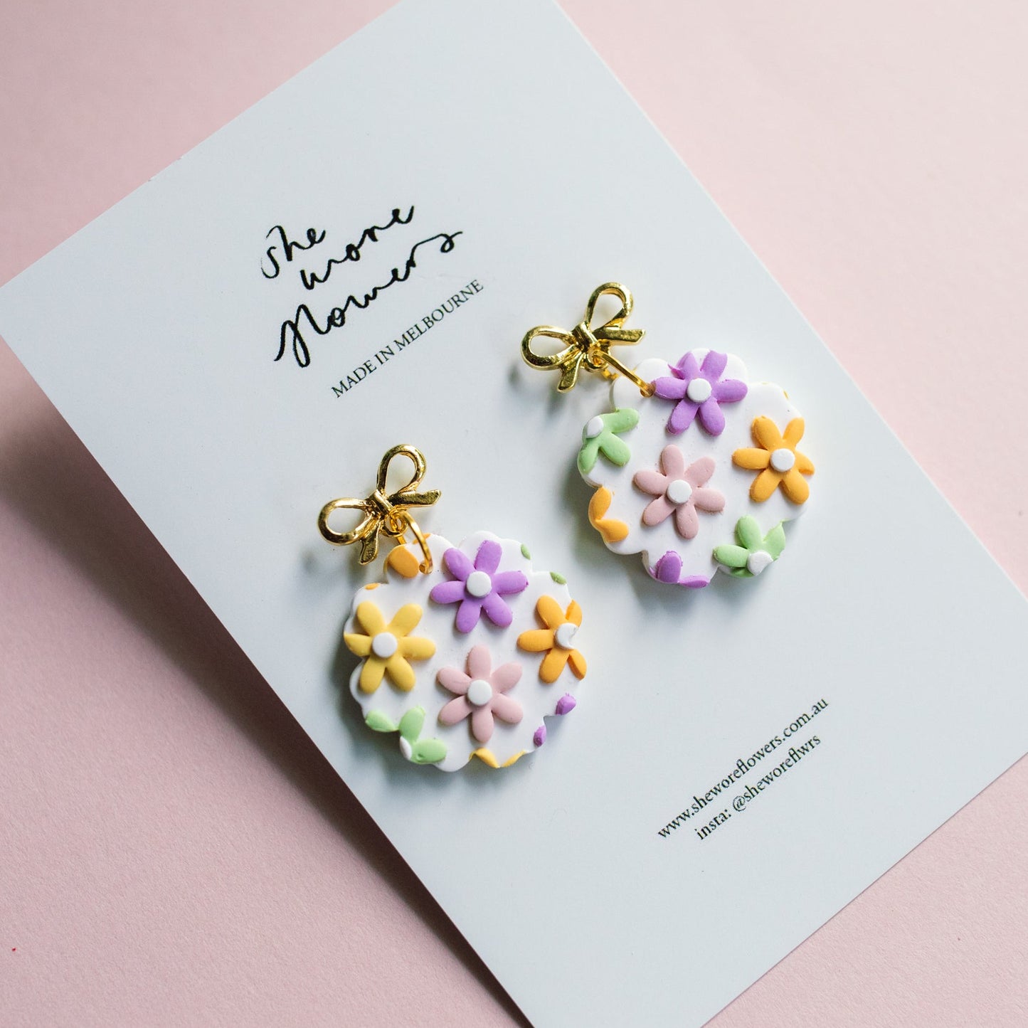 Pair of floral earrings on a card with 'She wore flowers' text on a pink background