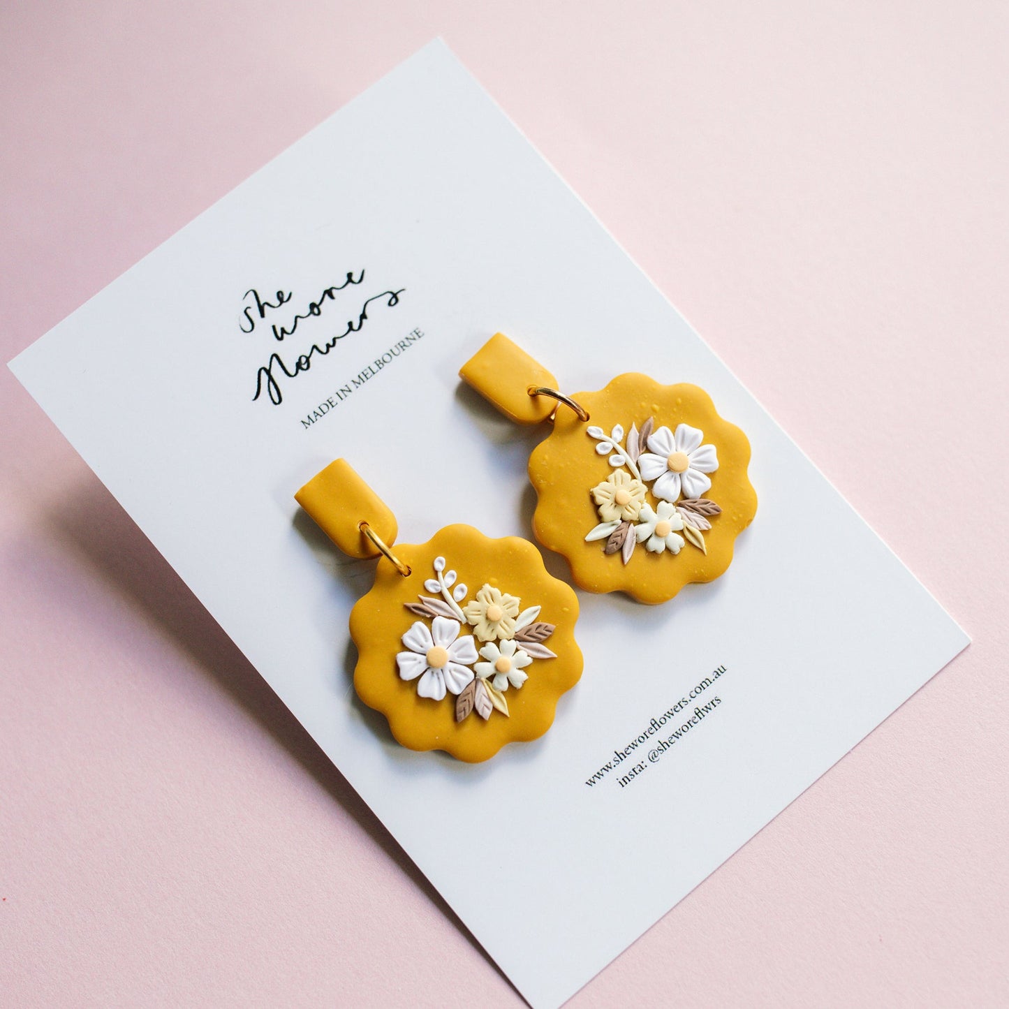 Yellow floral earrings on a white card with text on a pink background