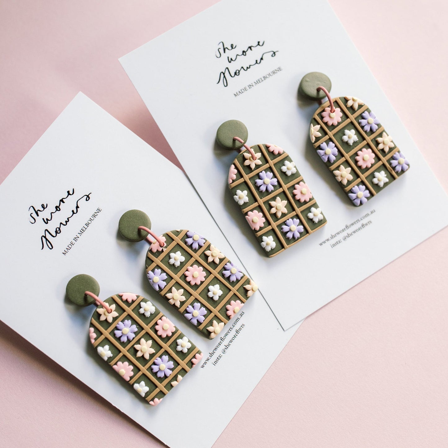 Decorative earrings on a card with 'She's One Flower' text on a pink background