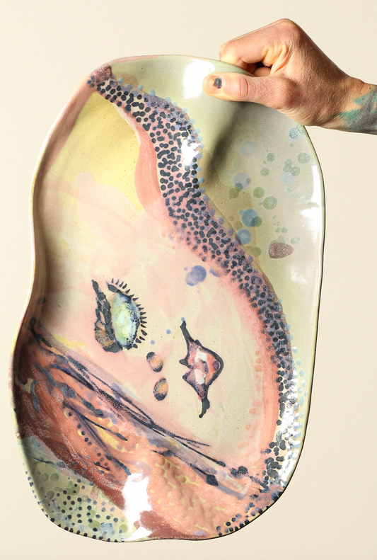 Hand holding a ceramic plate with artistic design on a beige background